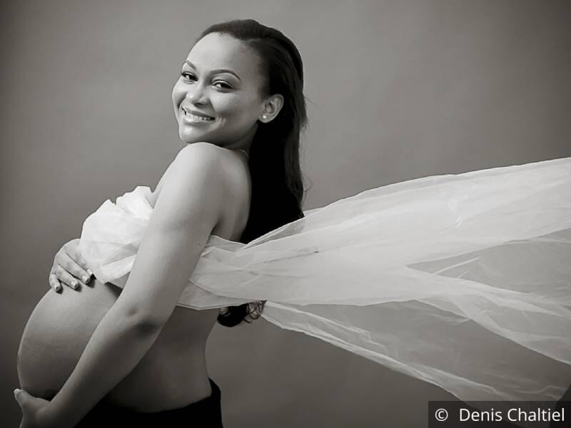 Photo en noir et blanc d'une femme enceinte avec un voile volant derrière elle.